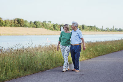 Smiling senior couple walking with arm around on road