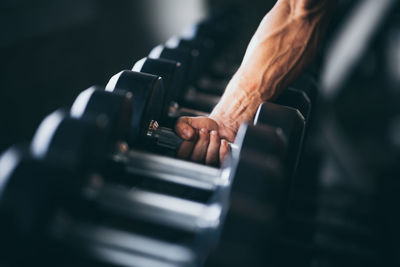 Cropped hand of man holding dumbbell in gym