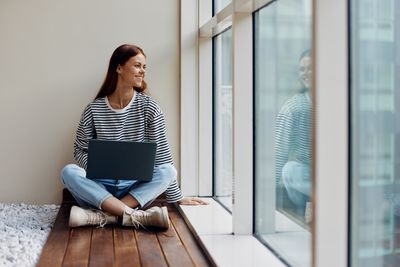 Young woman sitting on window