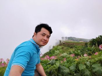 Portrait of man by plants against sky during foggy weather