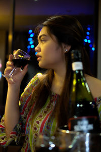 Young woman looking away while drinking wine