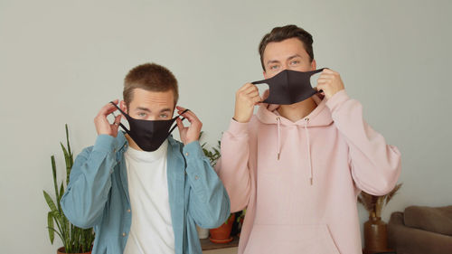 Portrait of gay couple wearing mask at home