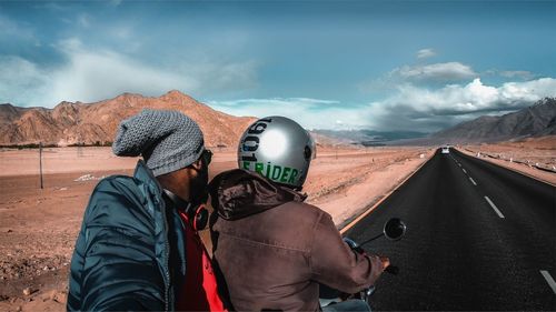 Rear view of man and woman on mountain against sky