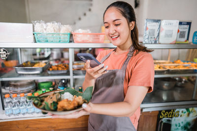 Portrait of smiling young woman using mobile phone in cafe