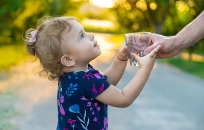 Cropped hand of father giving drinking water at park