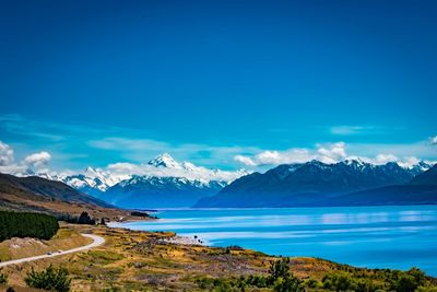 Scenic view of river by mountains against blue sky