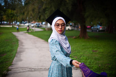 Portrait of smiling young woman standing on footpath