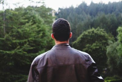 Rear view of a man standing against trees