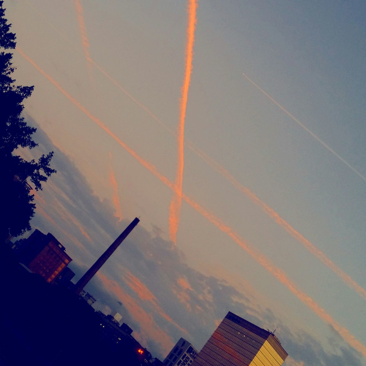 building exterior, architecture, built structure, sky, low angle view, sunset, city, cloud - sky, vapor trail, outdoors, orange color, building, no people, tall - high, cloud, nature, skyscraper, high section, dusk, development