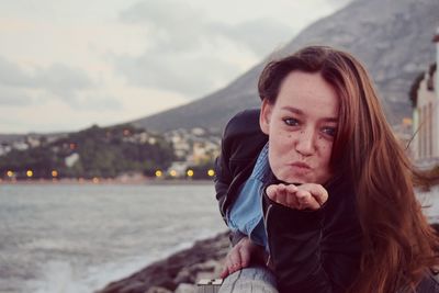 Close-up portrait of puckering while gesturing against sea