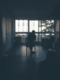 Silhouette people sitting on chair by window