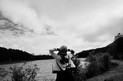 Woman standing by lake against sky