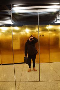 Reflection of man photographing on mirror in restroom