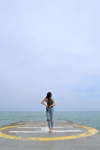 Woman standing on footpath against sea