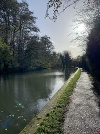 Scenic view of canal by trees against sky