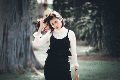 Portrait of young woman standing at park