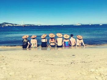 Full length of people standing on beach against clear sky