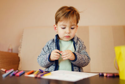 Boy making drawing on table at home