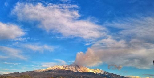 Low angle view of volcanic mountain against blue sky