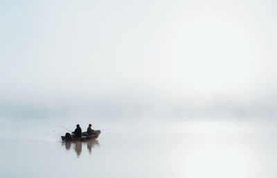 People on boat in sea against sky