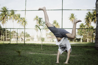 Side view of man skateboarding on field against trees