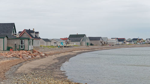 Houses on beach by buildings against sky