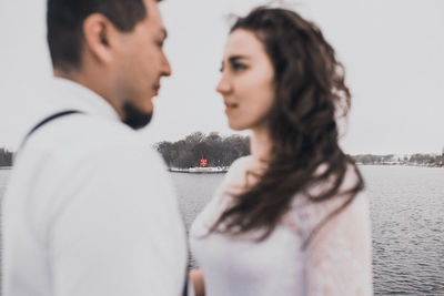 Side view of young woman standing against sea