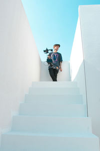 Low angle view of man standing on staircase with a camera