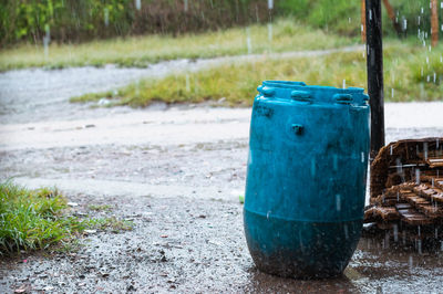 Blue trash can placed in the middle of a dirt road in a poor neighborhood, placed in the middle 