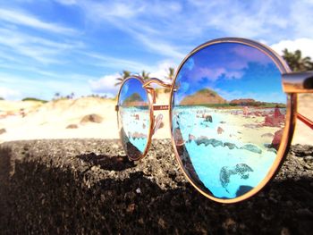 Close-up of sunglasses with beach reflection during sunny day