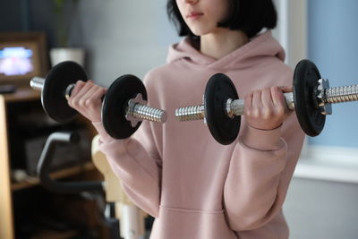 Girl sports with dumbbells in the room