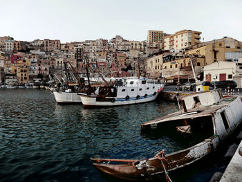 Boats moored at coastline by city