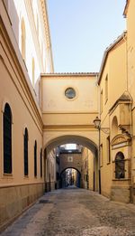 Empty alley amidst buildings in city against sky