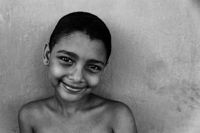 Portrait of smiling young woman against wall