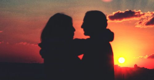 Silhouette couple against orange sky during sunset
