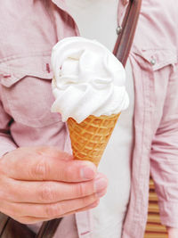 Man in light red shirt holds big tasty waffle cone with ice-cream. cold dessert for summer 