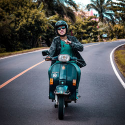 Portrait of young woman riding motorcycle on road