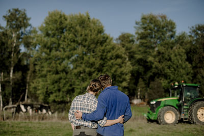 Couple with arms around standing in farm on sunny day