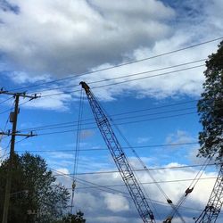 Low angle view of electricity pylon against cloudy sky