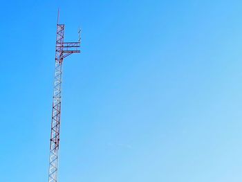 Low angle view of communications tower against blue sky