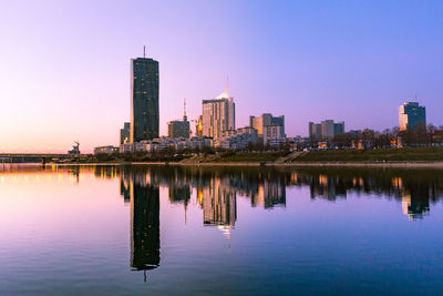 Reflection of buildings in lake against clear sky