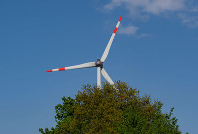 Low angle view of wind turbine against blue sky