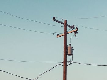 Low angle view of electricity pylon against clear sky