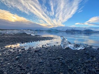 Scenic view of sea by snowcapped mountains against sky during winter