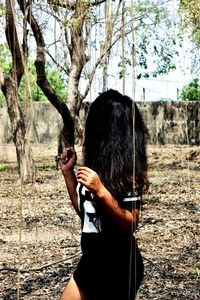 Rear view of woman standing against trees