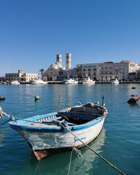 Boats moored in sea against clear blue sky