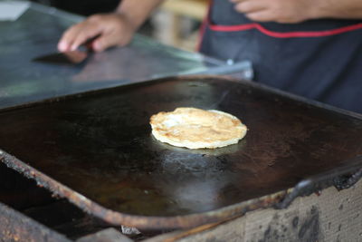 Midsection of person preparing food in cooking pan