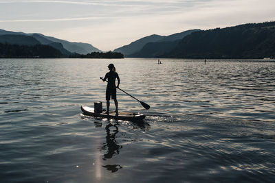 A young woman paddles a sup on the columbia river during a sunny day.