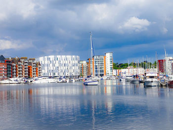 Boats moored in harbor against buildings in city