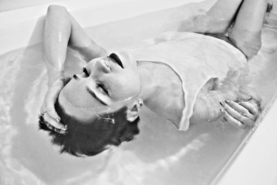 High angle view of fashion model bathing in bathtub at home